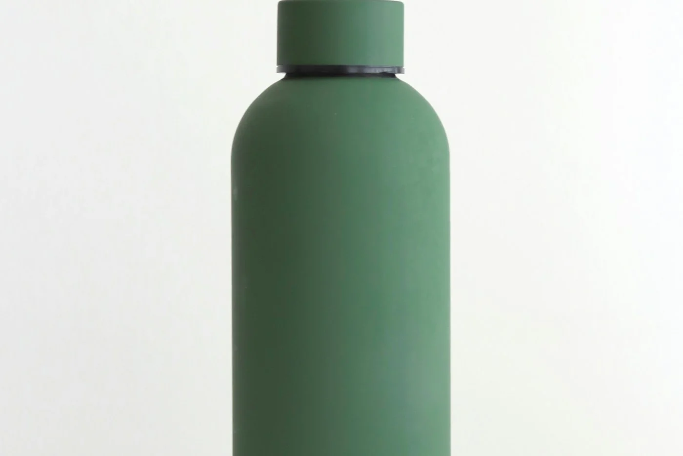 A green reusable water bottle with a screw cap against a light background.