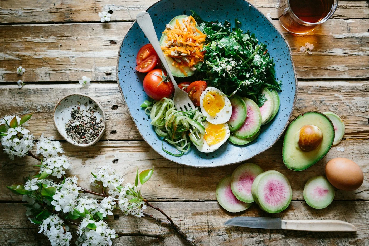 Eggs, vegetables, and avocado arranged as a colorful meal on a blue plate.