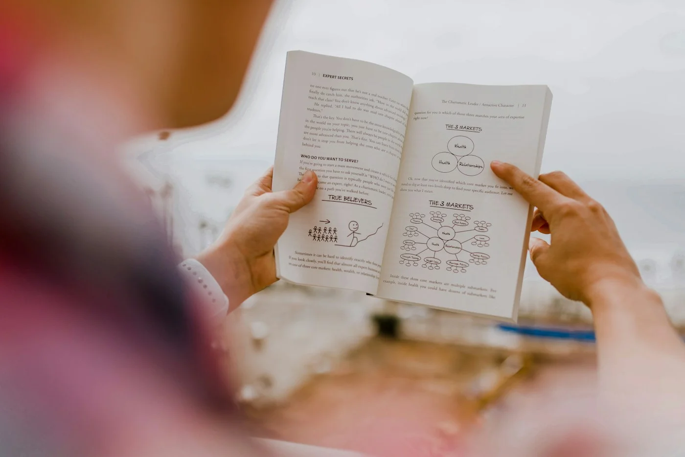 A person holding an open book and reading its pages.