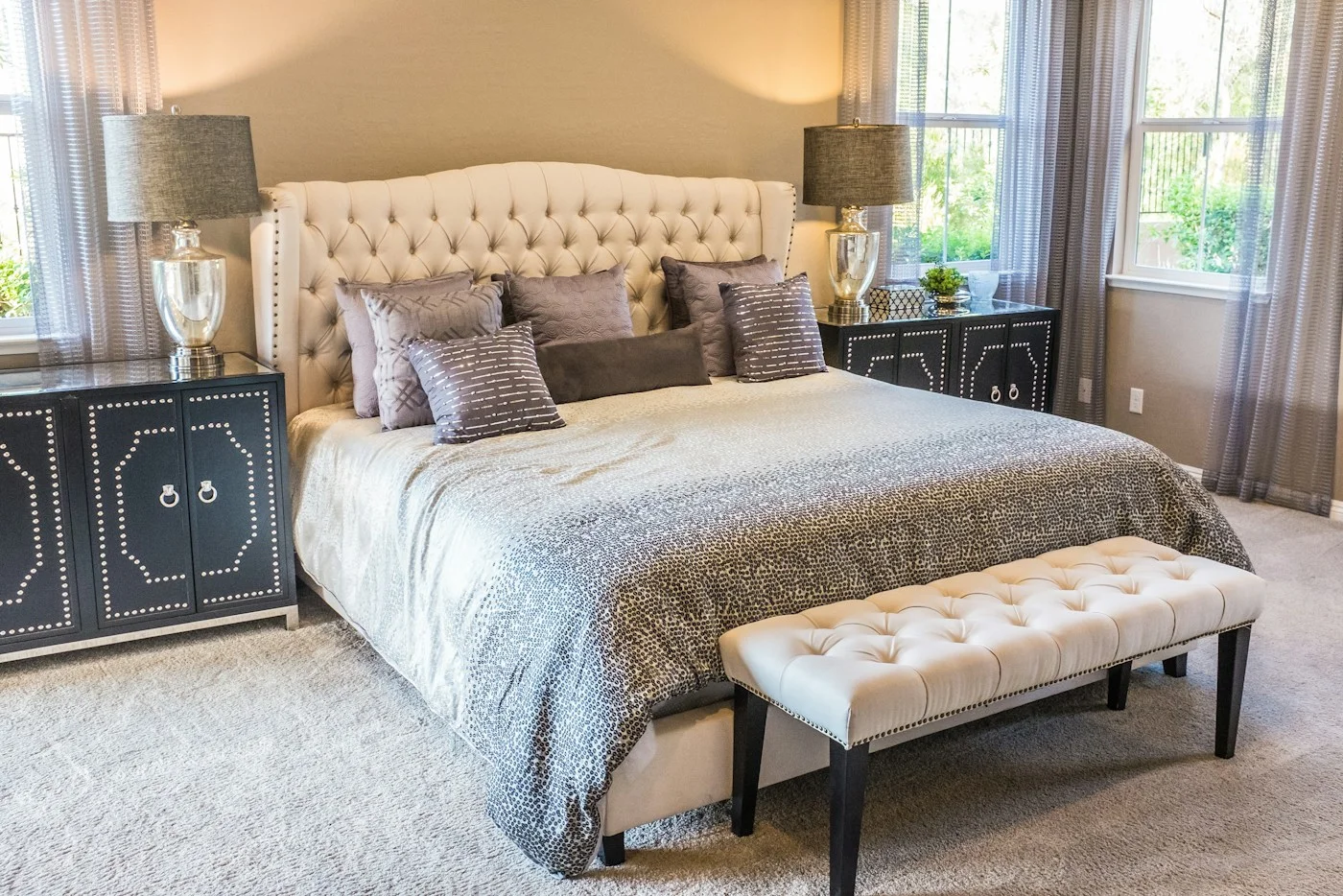 A bedroom with an upholstered bed, curtains, and bedside lighting.