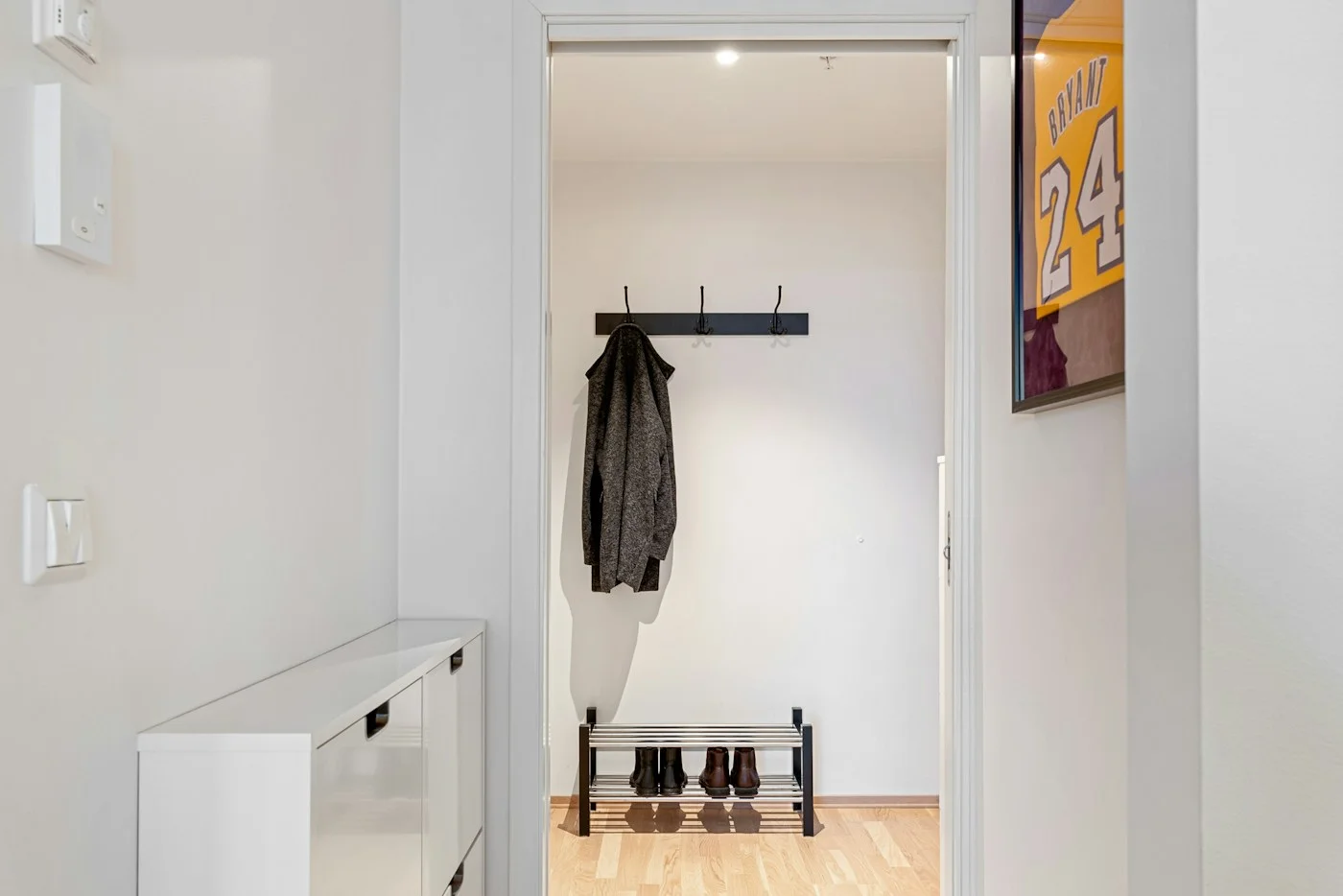 A white home hallway with coat hooks and shoes near the entrance.